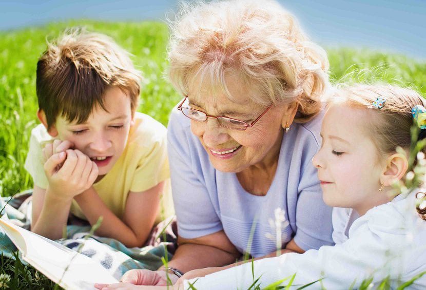 Abuela leyendo con sus nietos en el pasto