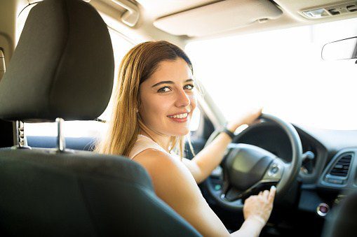 Joven sonriente conduciendo su primer auto