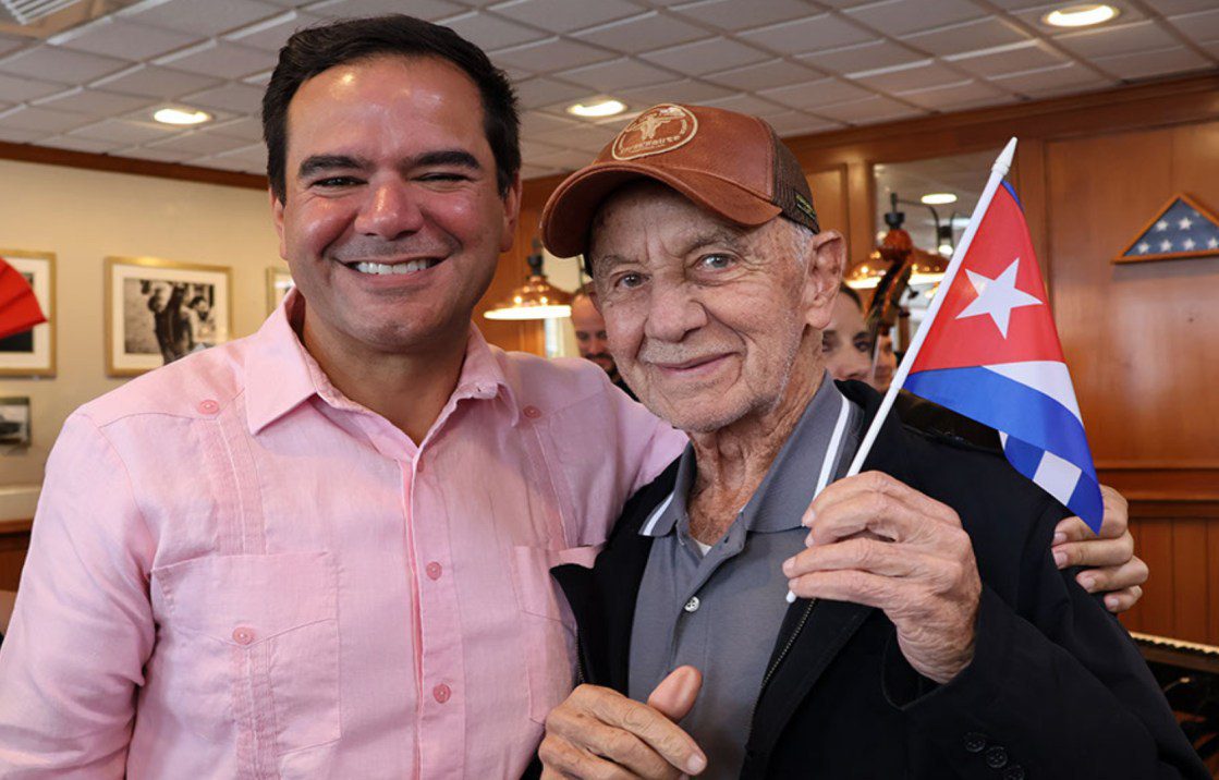 El Comisionado Ralph Rosado junto a un adulto mayor con bandera cubana
